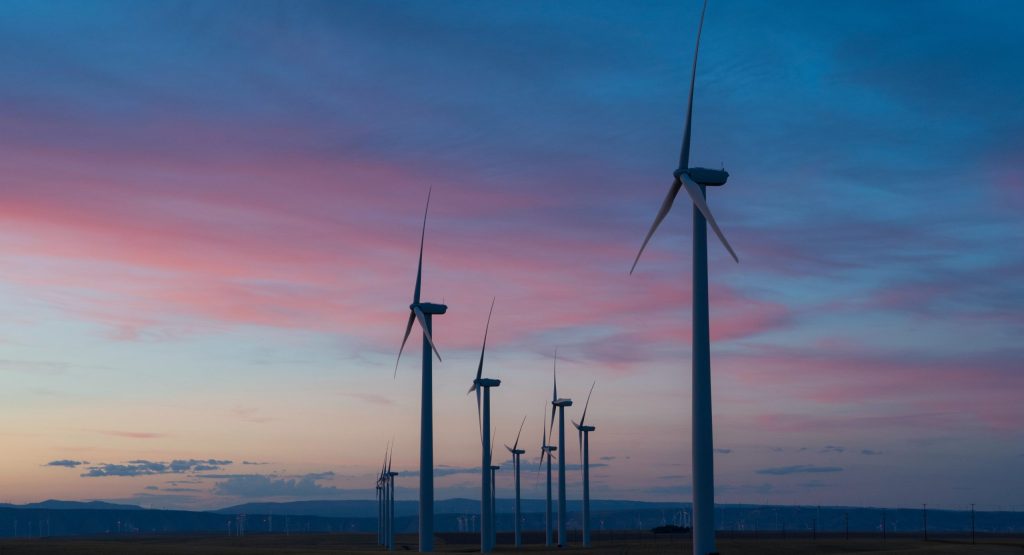 A sunset view over a line of windfarm turbines demonstrates renewable power generation for your decarbonisation strategy