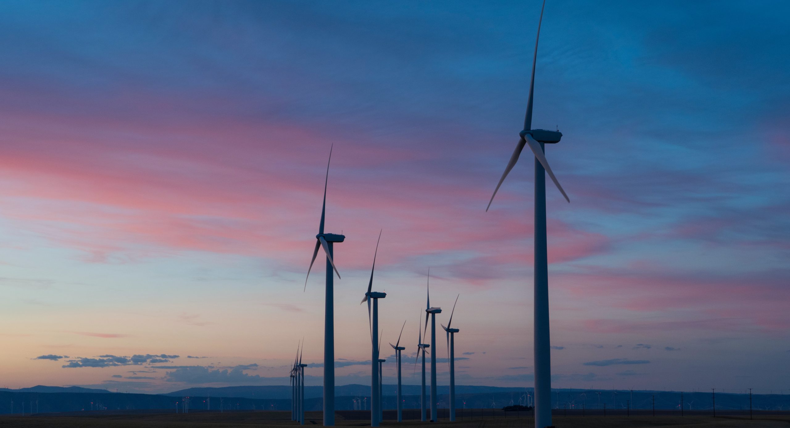 A sunset view over a line of windfarm turbines demonstrates renewable power generation for your decarbonisation strategy